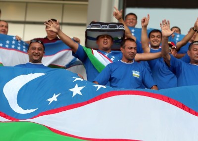 Uzbekistan fans hold up their national flag as they watch their national team play against Qatar during their group B 2014 World Cup Asian qualifying football match in Doha on October 16 , 2012. AFP PHOTO/KARIM JAAFAR ==QATAR OUT==        (Photo credit should read KARIM JAAFAR/AFP/Getty Images)